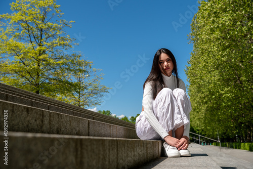 Young woman with dark hair sitting on stairs outdoor