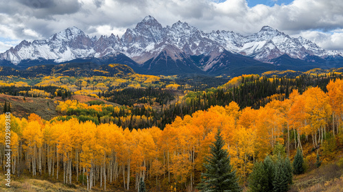 Majestic autumn landscape featuring vibrant orange aspens in the foreground and snow-capped mountains