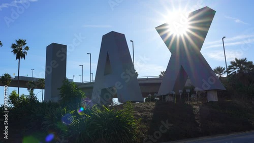Los Angeles, California - January 6, 2025: Large blue LAX sign set against a backdrop of a clear blue sky and lush greenery.