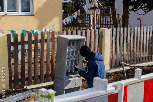 Technician working on a fiber optic distribution cabinet during street construction..