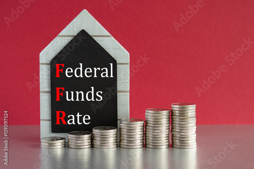 FEDERAL FUNDS RATE symbol. Concept words FEDERAL FUNDS RATE written on a black board. Silver coins arranged in a graph in front. Beautiful red background, grey table. Business concept.