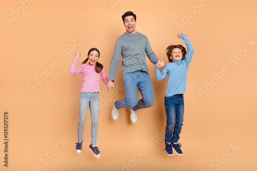 Happy family jumping joyfully against beige background showcasing positive energy, bonding and love in casual outfits with cheerful smiles