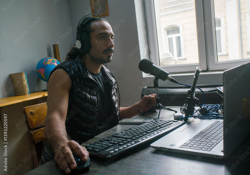 Blogger and musician from Iran wrking in Internet on laptop in hostel ouside of Motherland