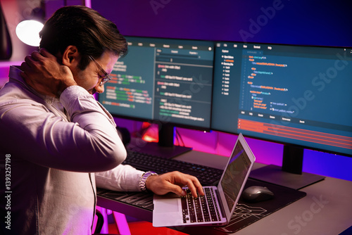 Obraz na płótnie IT developer being tried of overwork on solve problem in error software coding system with sitting to stretch body, concept of programmer working online website database at neon light office. Surmise. w salonie