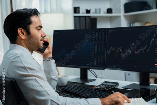 Trader businessman calling to consultant or partner with two stock exchange investment, compare data analysis to invest high profit value dynamic financial technology stock market at office. Surmise.