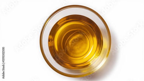 Golden Oil: Clear glass bowl with smooth, shiny golden-yellow liquid, placed on a white surface. Overhead view highlighting the depth and clarity of the liquid.