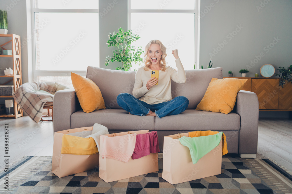 Blonde woman sitting casually on a modern couch surrounded by colorful shopping bags, smiling joyfully in a cozy well lit home interior. Blonde woman sitting casually on a modern couch surrounded by colorful shopping bags, smiling joyfully in a cozy well lit home interior.