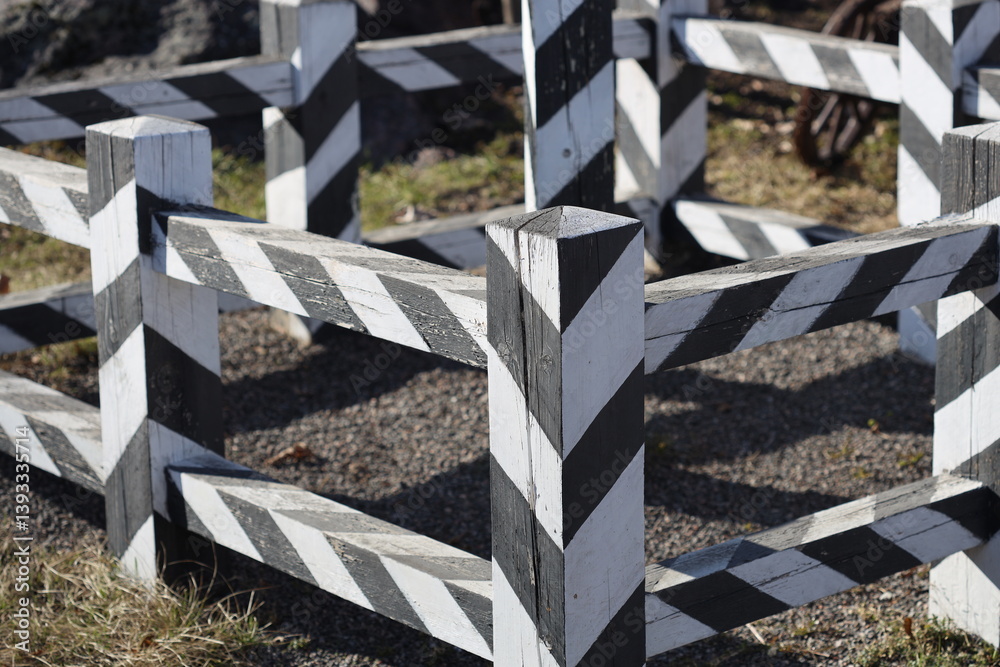 A simple fence with alternating stripes of white and black in an open field.