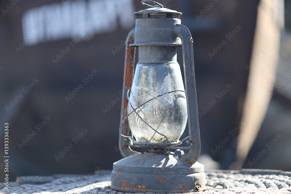 An old lantern sits on a rock in the outdoors.