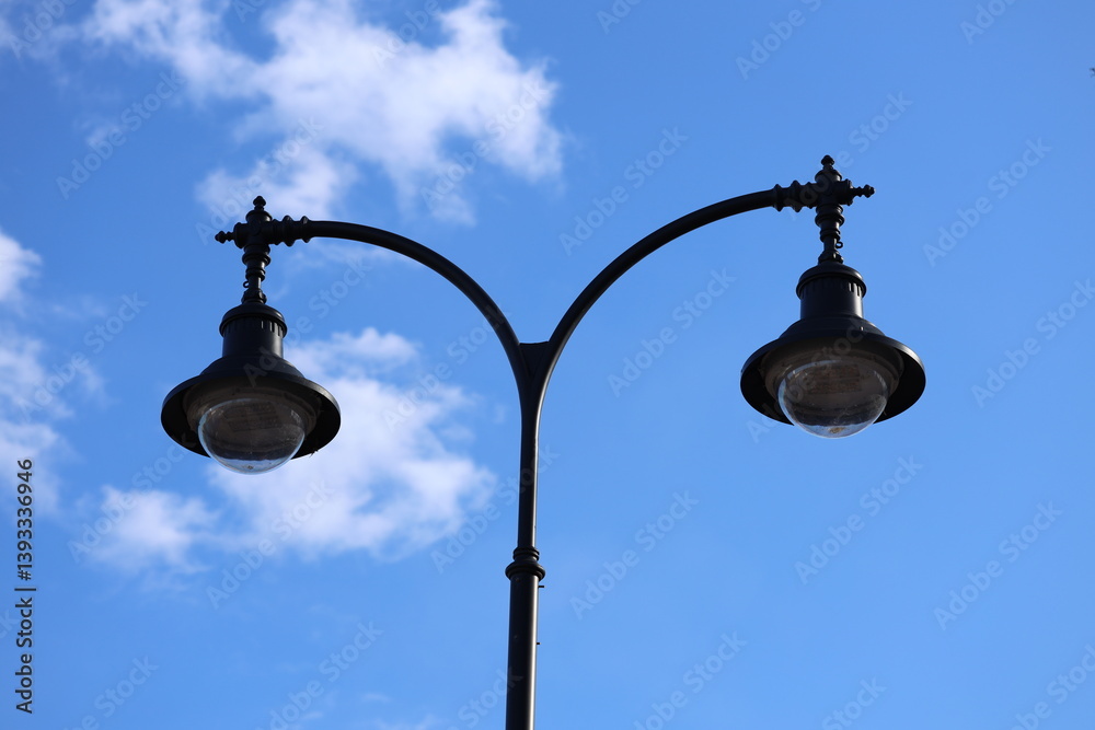 A single street light stands on a pole against a bright blue sky.