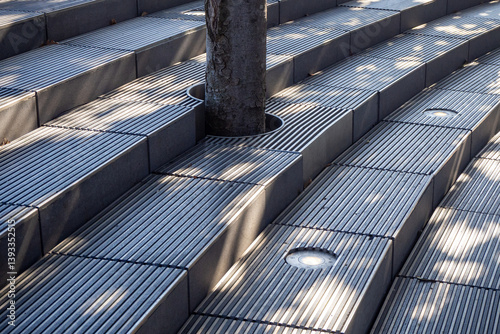Metal steps with round lights and lattice around tree trunk. Fragment of aesthetic urban environment