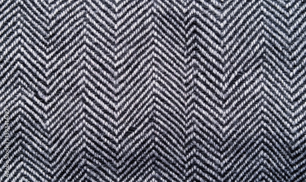 A detailed close-up reveals the intricate texture of a classic black and white herringbone fabric pattern. A detailed close-up reveals the intricate texture of a classic black and white herringbone fabric pattern.
