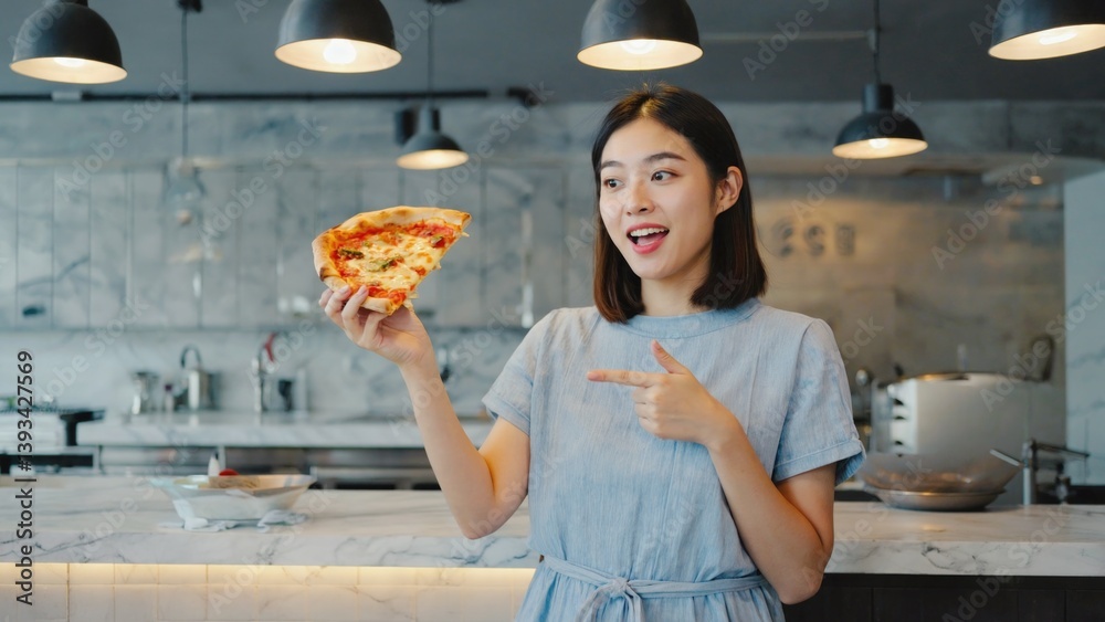 A woman holds up a slice of pizza, ready to be enjoyed