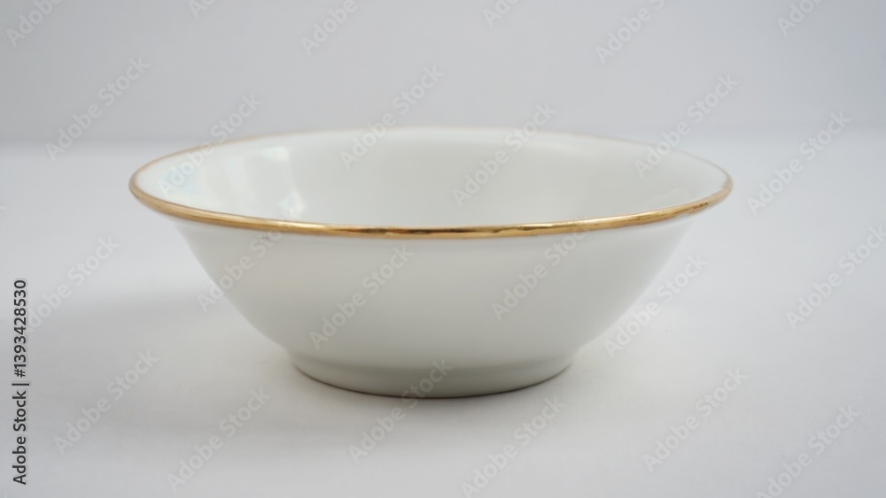 A white bowl with a gold rim sitting on a table, perfect for decorating or as a prop in a still life scene