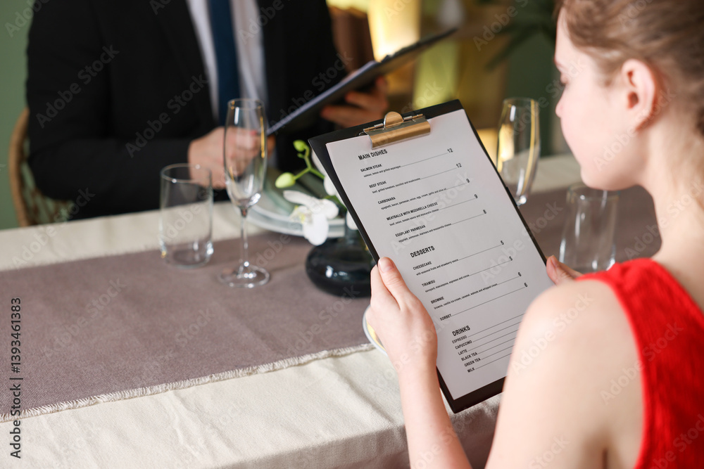 Couple choosing dishes from menu at table in restaurant, closeup Couple choosing dishes from menu at table in restaurant, closeup