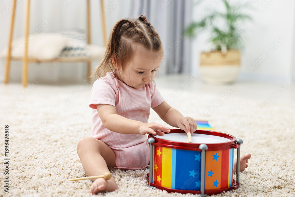 Cute little girl playing with toy drum and drumsticks on floor at home