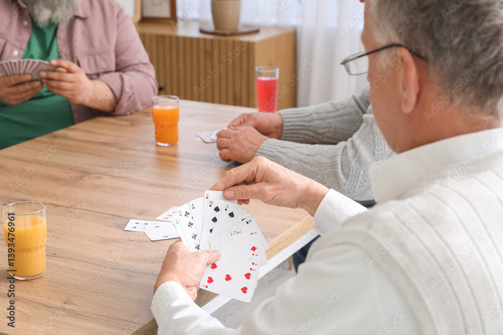Elderly men with drinks playing cards at home, closeup