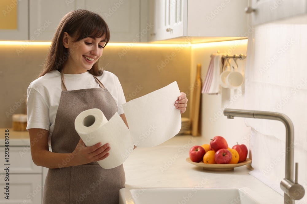 Happy woman using paper towels in kitchen