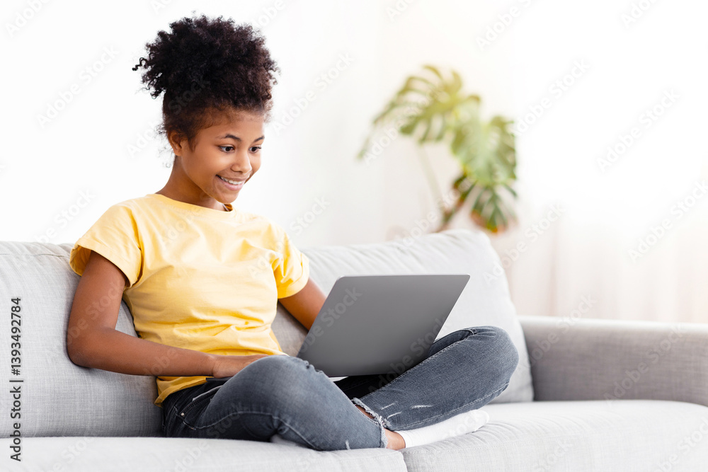 African Teen Girl Using Laptop Computer Browsing Internet Sitting On Couch At Home. Free Space African Teen Girl Using Laptop Computer Browsing Internet Sitting On Couch At Home. Free Space