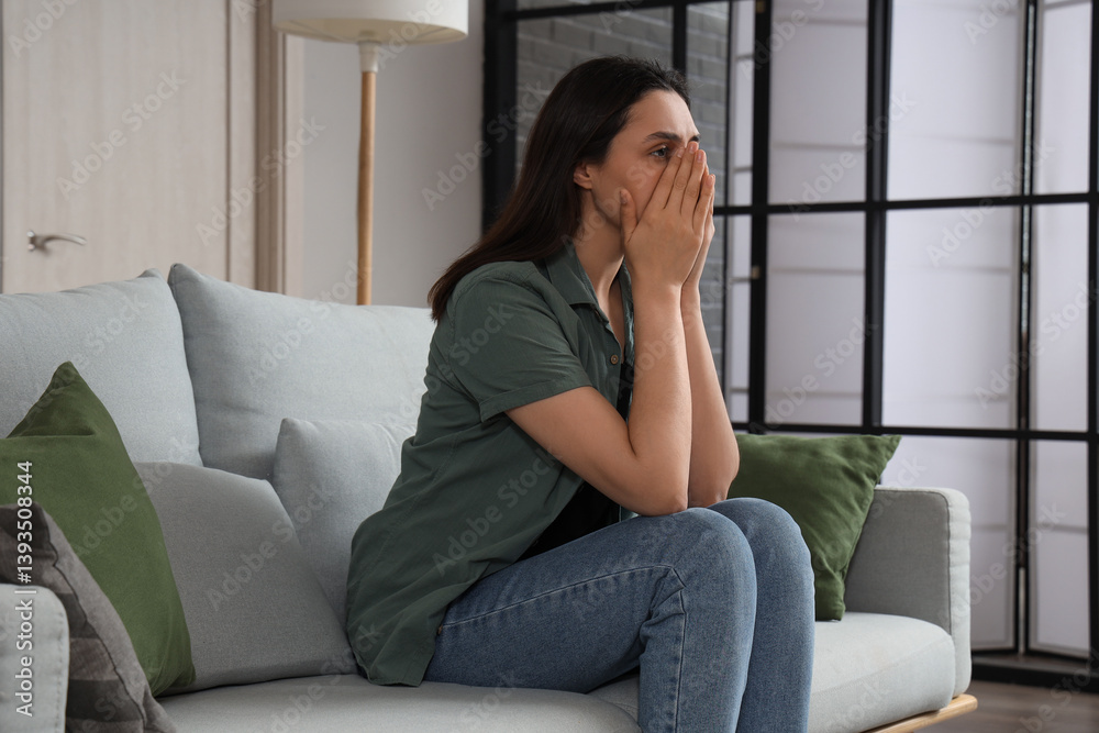 Depressed young woman sitting on sofa at home Depressed young woman sitting on sofa at home