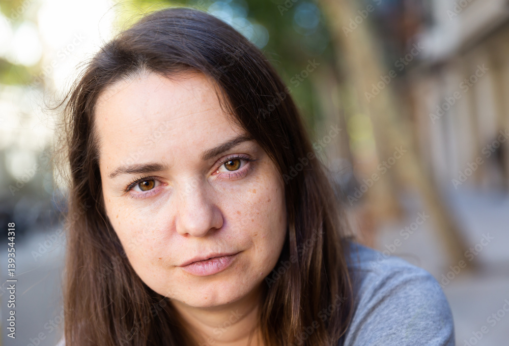 Obraz premium Closeup of dreamy face of attractive adult woman on blurred summer city street background