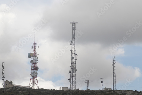 Telecom towers on a mountain ridge under a dramatic overcast sky. Telephone towers