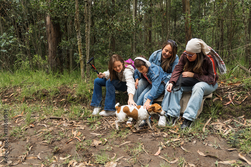 Family petting dog while resting during hike in forest
