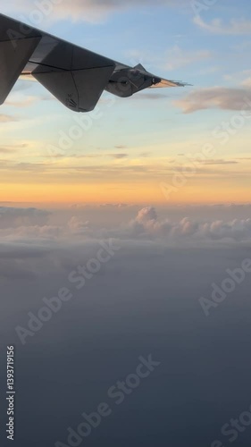 Wing view with peach-orange sunset sky transitioning to gray. Wispy multi-layer clouds create dramatic aerial perspective.