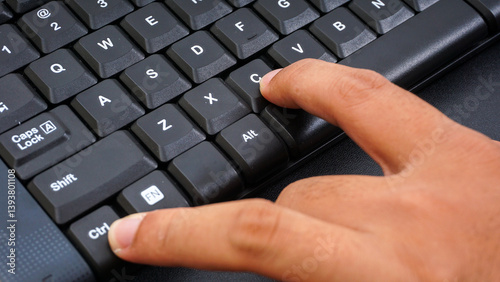 Close up on finger pressing ctrl or control and c or ctrl + c shortcut keys on a computer keyboard for copy isolated on black background