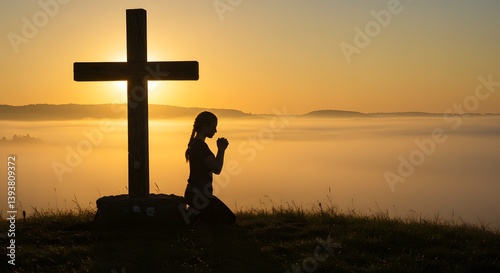 A person kneels in prayer before a large cross in a serene outdoor setting at sunrise, enveloped in golden mist, reflecting solitude, faith, and devotion.