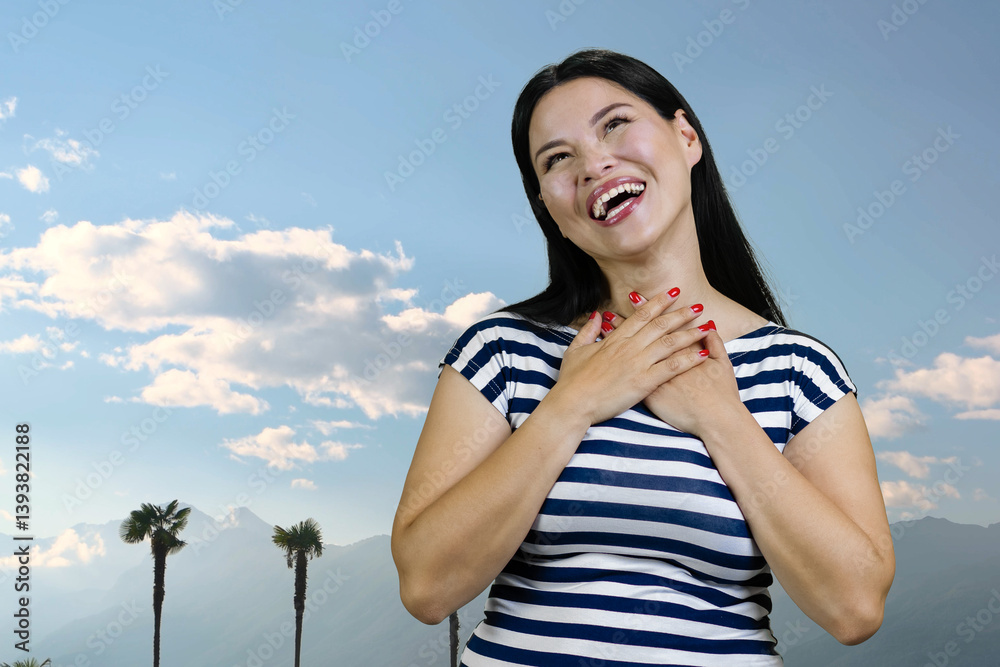 Fototapeta premium Young asian brunette woman is laughing hard standing outdoors. Blue sky background.