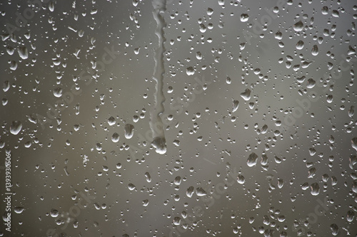 Window covered in glistening raindrops creates a soothing and textured background on a rainy day.