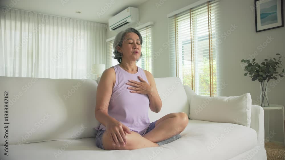 Asia adult aged people middle age mindful happy old woman reduce hot flash sit at home sofa yoga zen calm stress relief deep meditate self love relax elder aging life asian female mental health care.