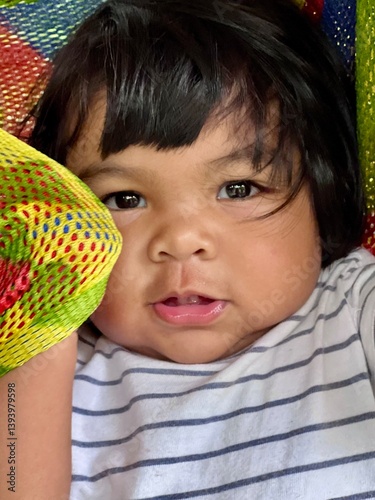 Cute Asian baby girl looking at camera on colorful background.