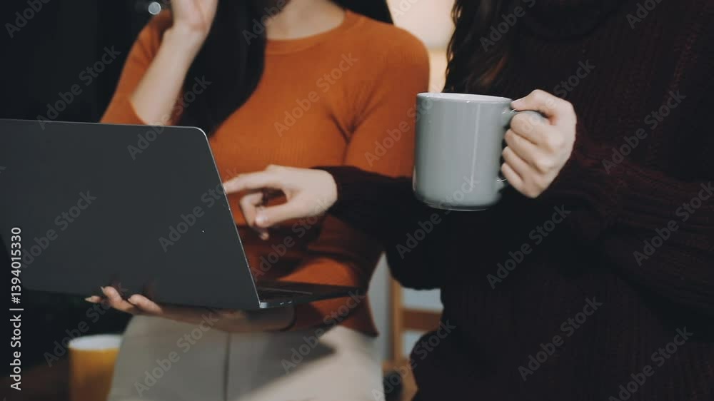 Asian woman sitting at a living room table working with a laptop and headphones. Asian woman sitting at a living room table working with a laptop and headphones.