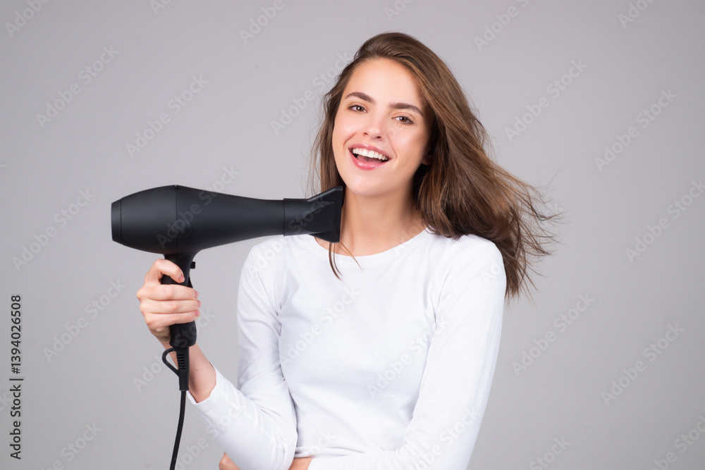 Brunette woman with hair dryer on studio background. Hairs style and beauty concept. Beautiful girl with hairdryer drying hair. Beauty model dries hair with hair dryer. Blow dryer.