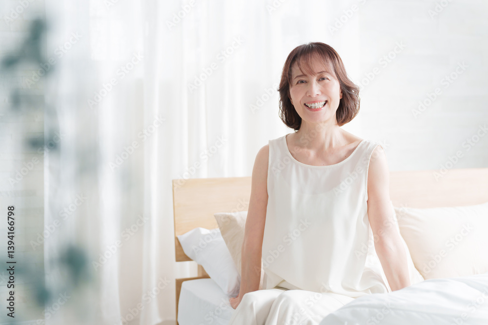 朝ベッドから起床する中高年女性 朝ベッドから起床する中高年女性