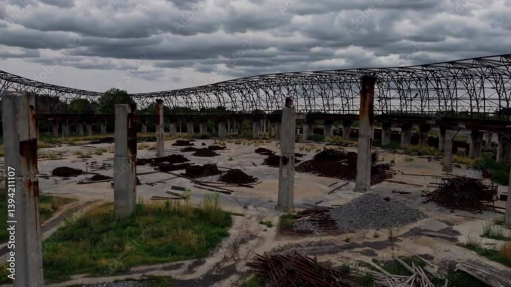 Dramatic clouds over abandoned industrial site with rusted framework and overgrown vegetation Dramatic clouds over abandoned industrial site with rusted framework and overgrown vegetation