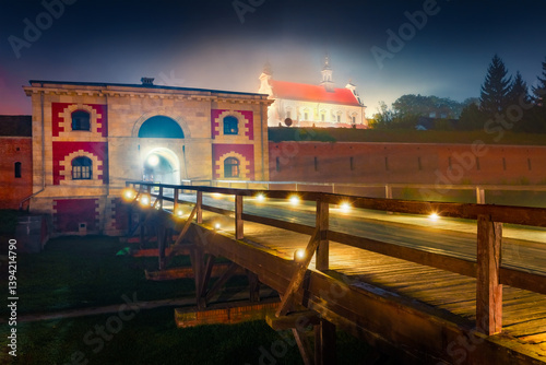 Obraz na płótnie Night summer view of fortress and city of Zamosc. Illuminated morning scene of walls of fortress and Szczebrzeska Gate with Cathedral of Resurrection and Saint on background, Zamosc. Poland, Europe. w salonie