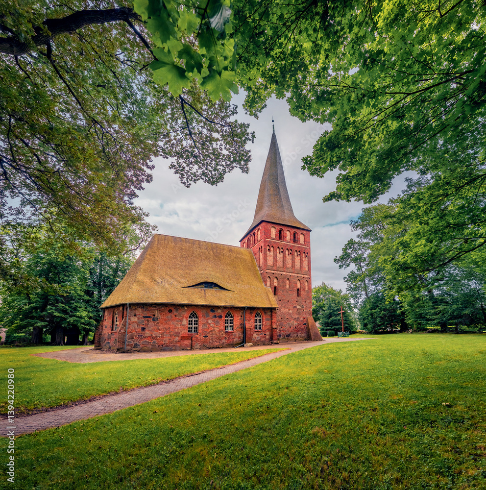 Fresh greenscene of beautiful old church of Polish Queen among foliage trees. Majestiv morning view of Iwiecino village, Koszalin County, West Pomeranian, Poland, Europe. Travel the world.