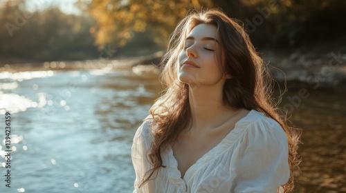 Beautiful young relaxed woman in white blouse enjoying nature breathing fresh air meditating on the river on an autumn day