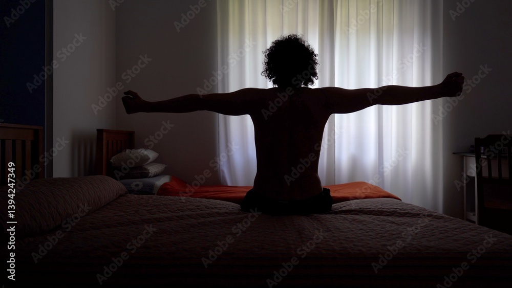 Man wakes up in the morning and gets out of bed to open the window curtains and look out of the house ready to start a new day - lifestyle in apartment
