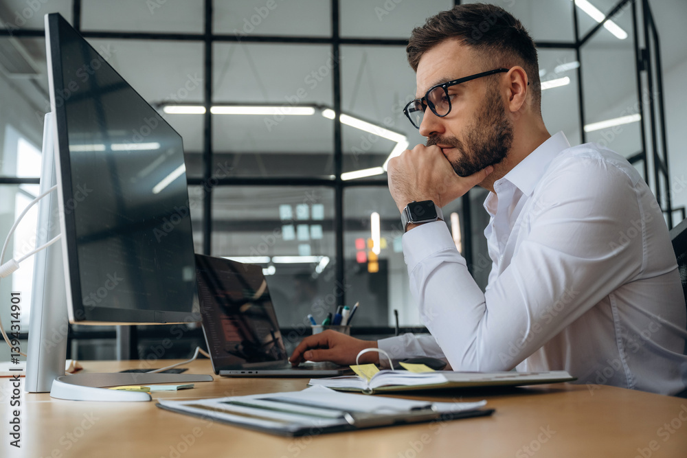 Fototapeta premium View from the side. Business person is sitting by computer in office and working