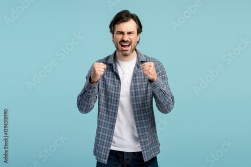 Photography Angry man shouting and showing fists on blue background