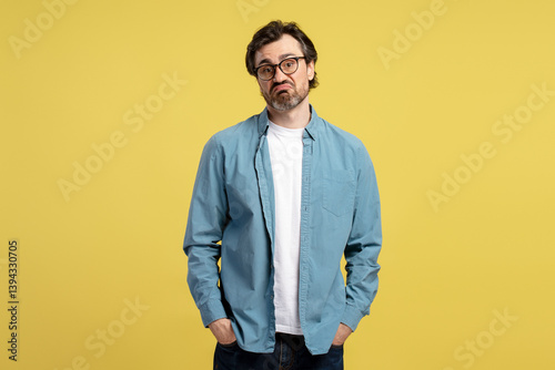 Canvas Print Sad man making a grimace with hands in pockets on yellow background