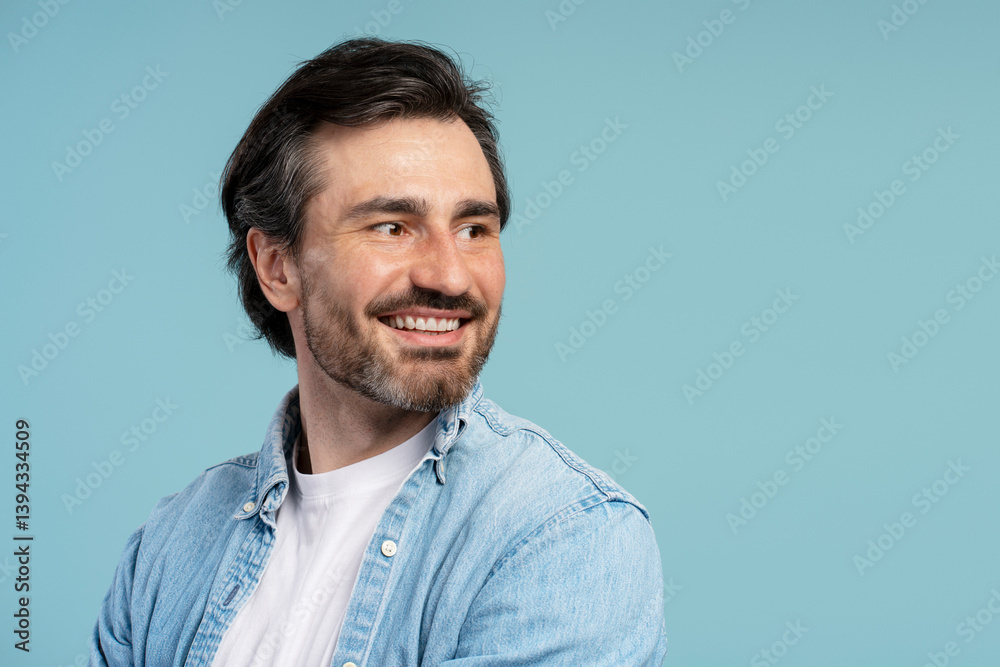 Fototapeta premium Smiling middle aged, bearded man looking away on blue background, copy space