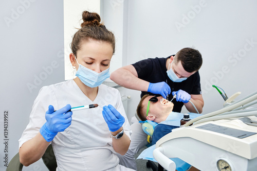 Dentist and Assistant Cementing Crown. Installing a dental crown. Teamwork in Dentistry.