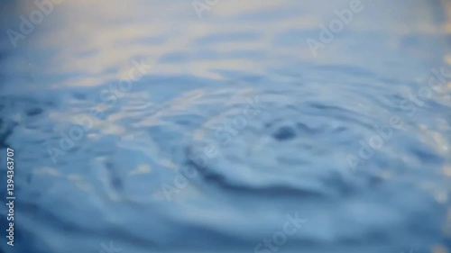 Slow motion video of water droplets falling into a calm pool, capturing ripple effects and fluid movement, perfect for relaxation visuals, meditation content, and nature themes


