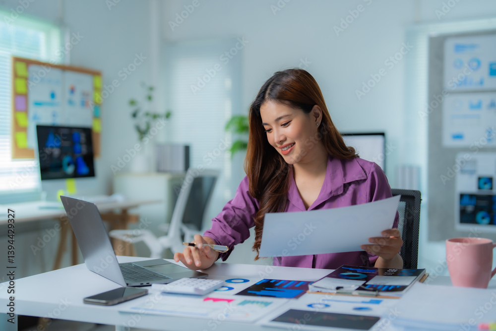 Young professional examining documents and using laptop, working with financial data and business reports in modern office workspace, demonstrating expertise in accounting and finance Young professional examining documents and using laptop, working with financial data and business reports in modern office workspace, demonstrating expertise in accounting and finance