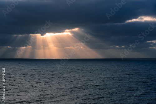 Sunbeams breaking through the storm clouds over the ocean